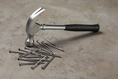 Photo of New hammer and metal nails on grey table. Professional construction tool