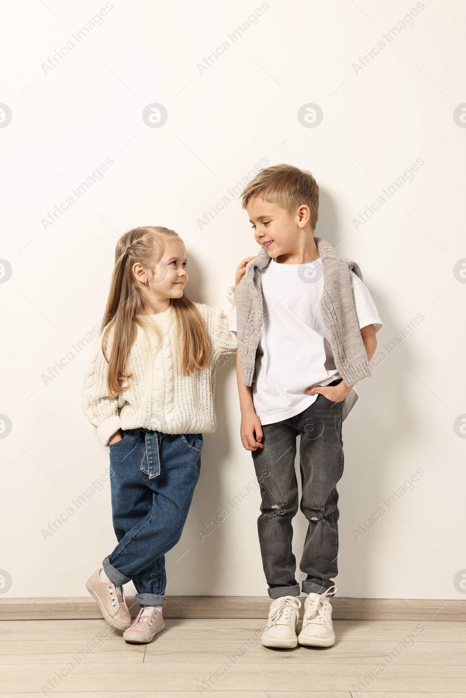 Photo of Fashion concept. Stylish children posing near white wall