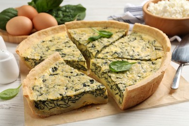 Photo of Cut delicious spinach pie on white wooden table, closeup