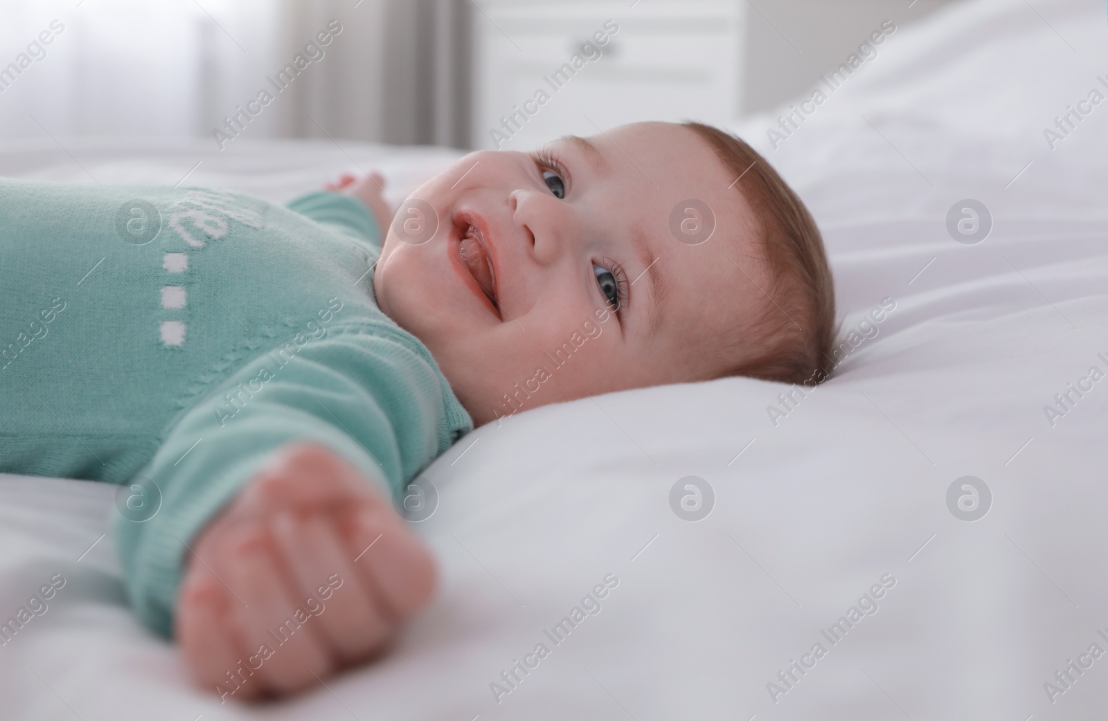 Photo of Cute little baby lying on bed with soft blanket indoors