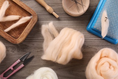 Photo of Felting wool and different tools on wooden table, flat lay