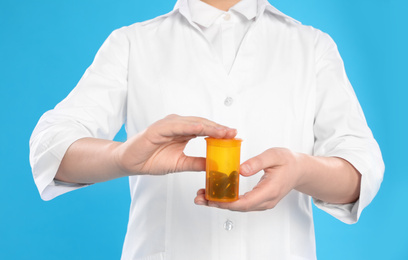 Photo of Professional pharmacist with pills on light blue background, closeup