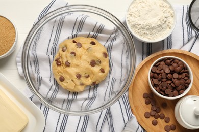 Fresh dough and different ingredients for cooking chocolate chip cookies on white table, flat lay