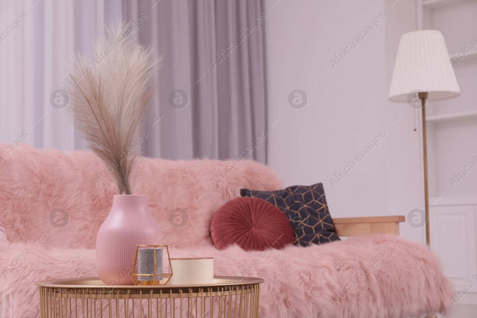 Photo of Vase and candles on coffee table near sofa in stylish room. Interior design