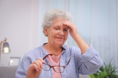 Photo of Senior woman with headache in room at home