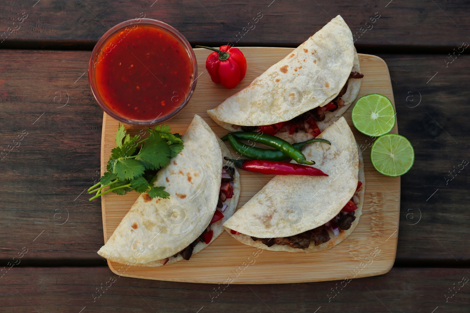 Photo of Delicious tacos with meat and vegetables on wooden table, top view