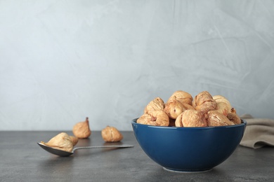 Photo of Bowl with dried figs on grey table, space for text. Healthy fruit