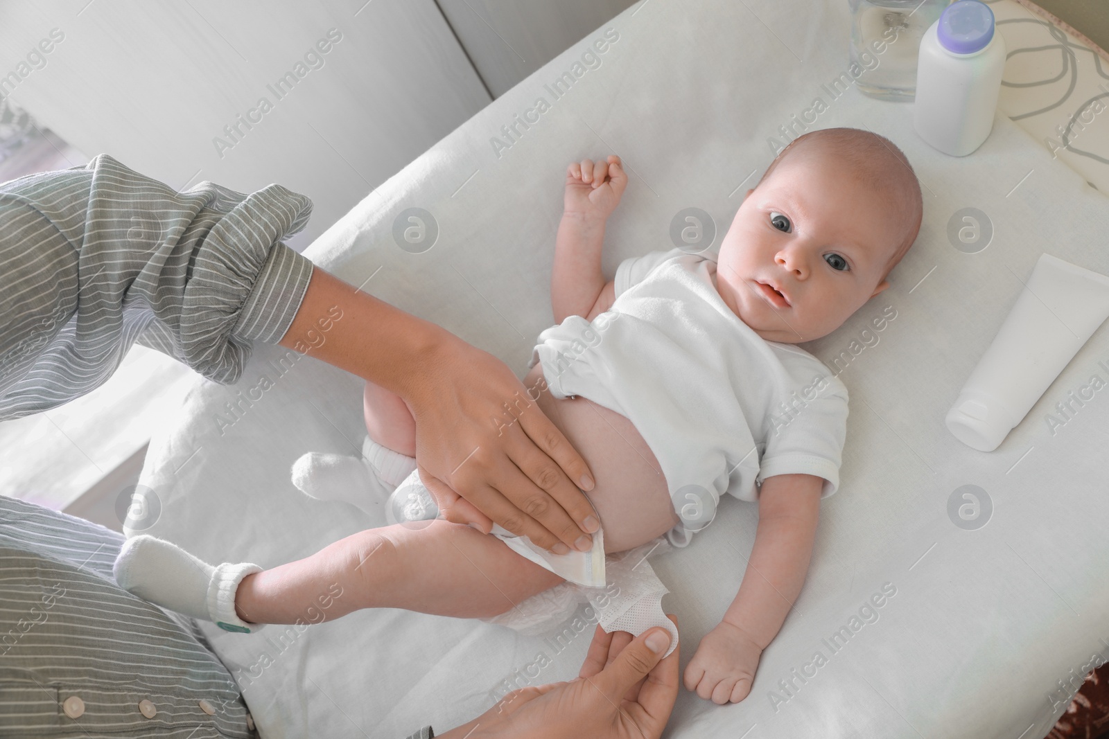 Photo of Mother changing her baby's diaper on table indoors, closeup