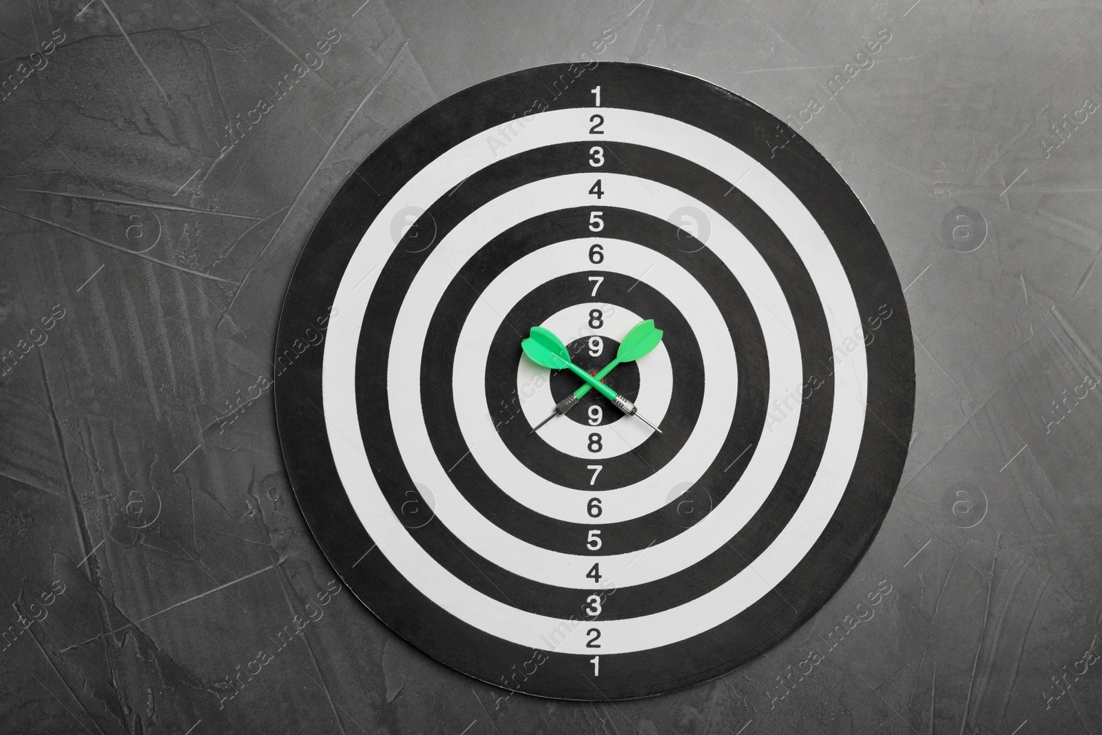 Photo of Dart board with color arrows on grey stone background, top view