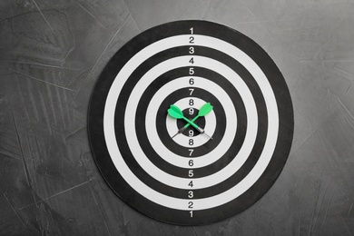 Dart board with color arrows on grey stone background, top view