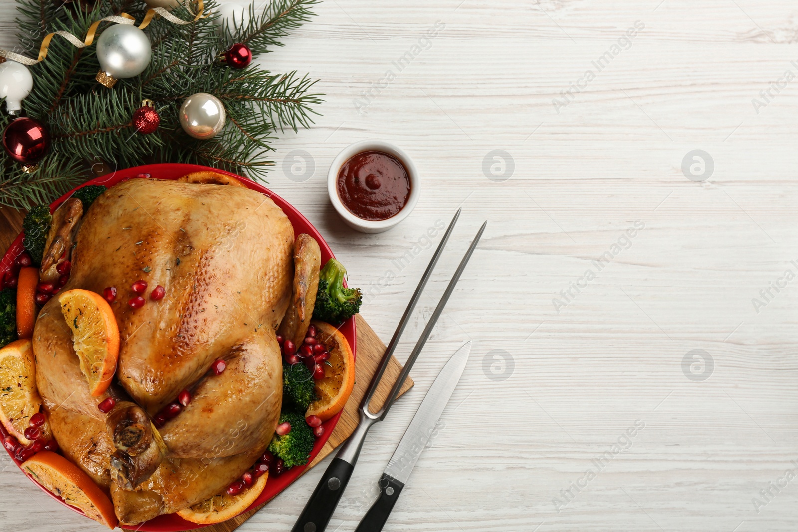 Photo of Delicious chicken with oranges, pomegranate and vegetables on white wooden table, flat lay. Space for text