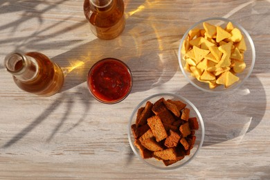 Different crispy rusks, beer and dip sauce on wooden table, flat lay