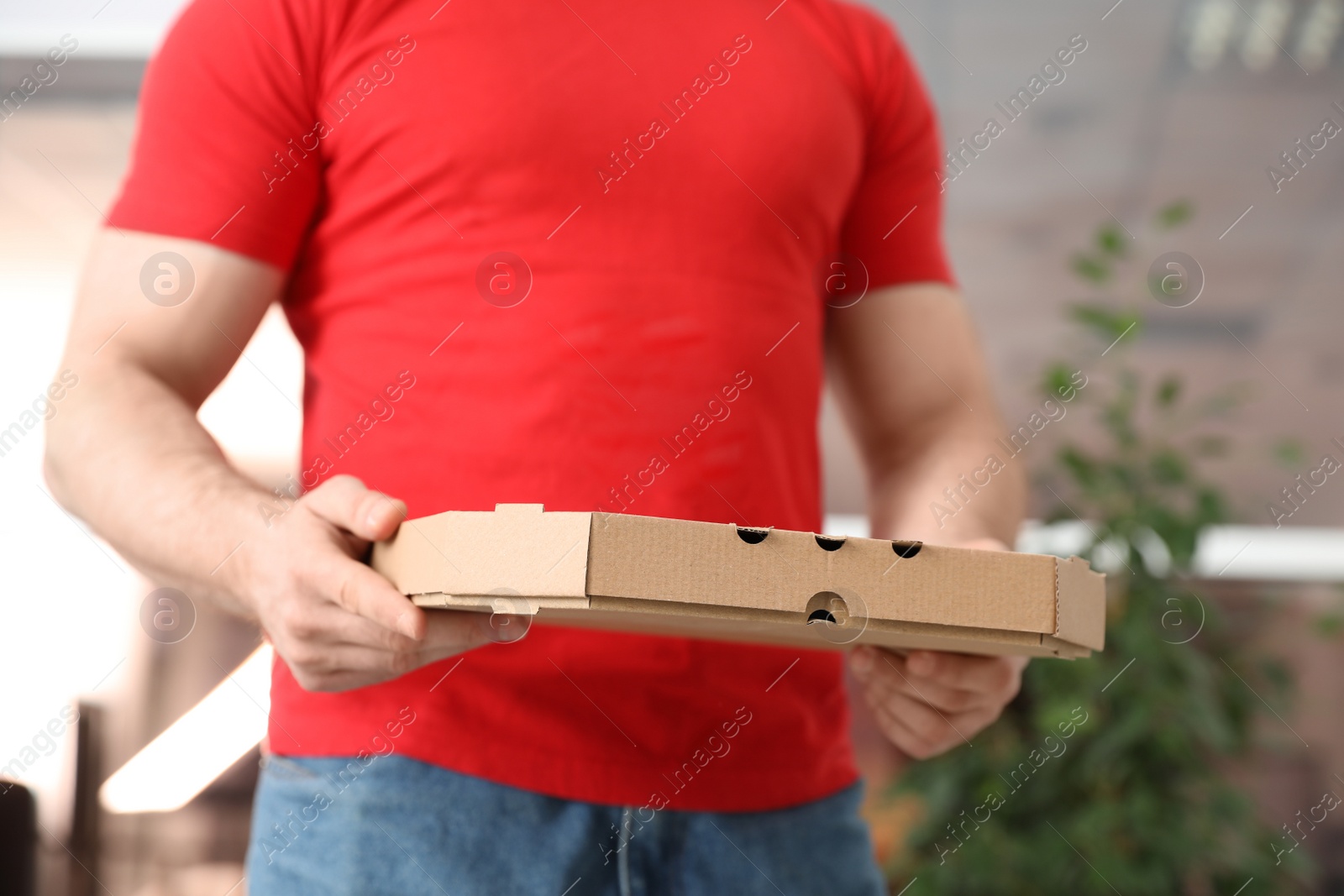 Photo of Courier with pizza box on blurred background, closeup