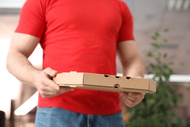 Courier with pizza box on blurred background, closeup