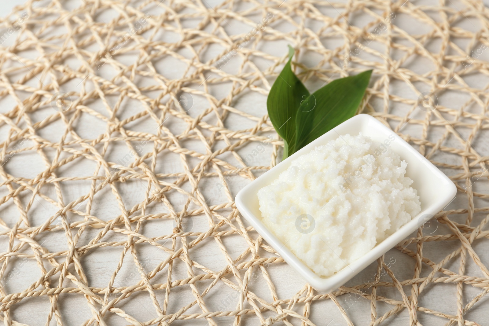 Photo of Shea butter in bowl on wicker mat. Space for text