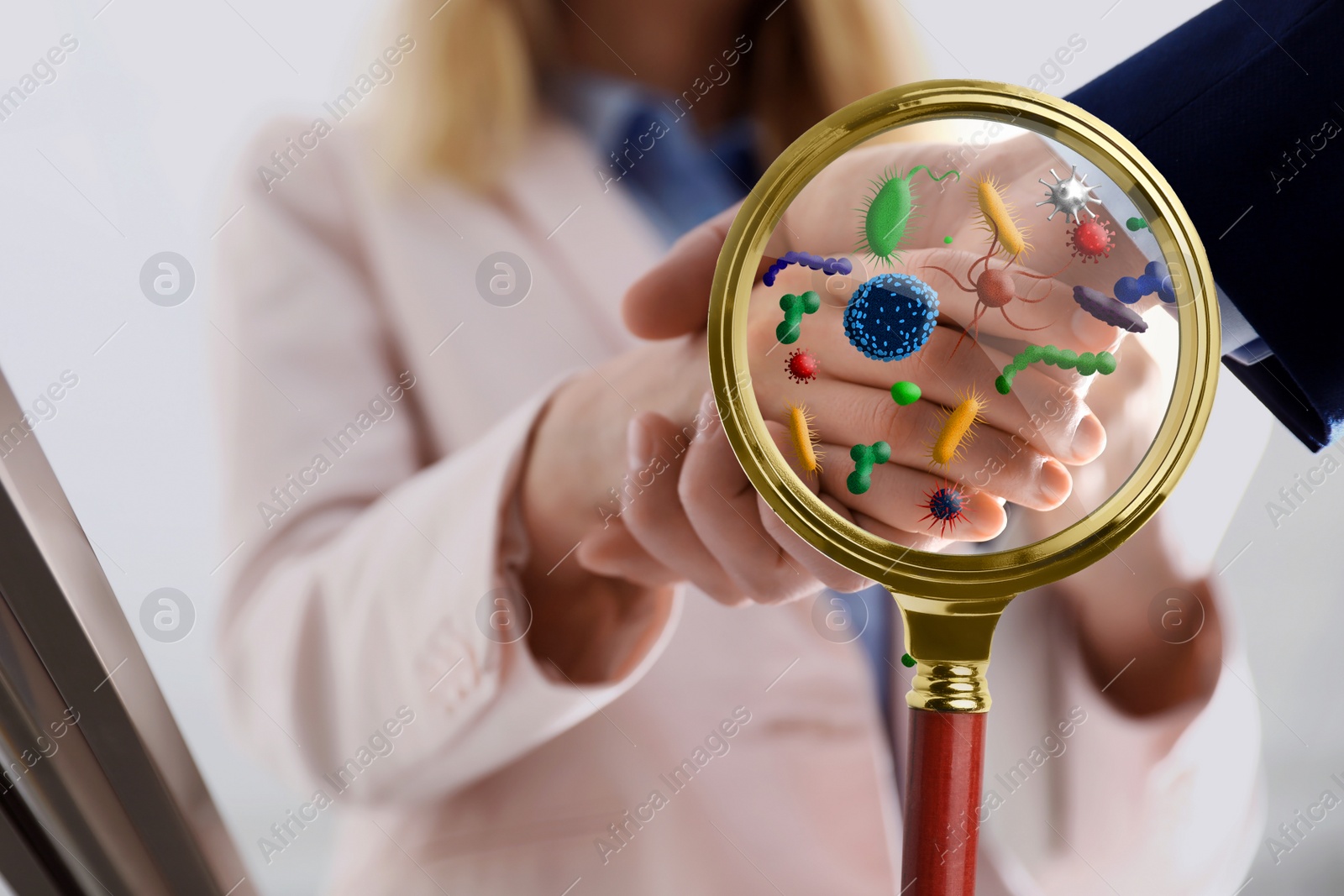 Image of Magnifying glass detecting microbes and business partners shaking hands, closeup