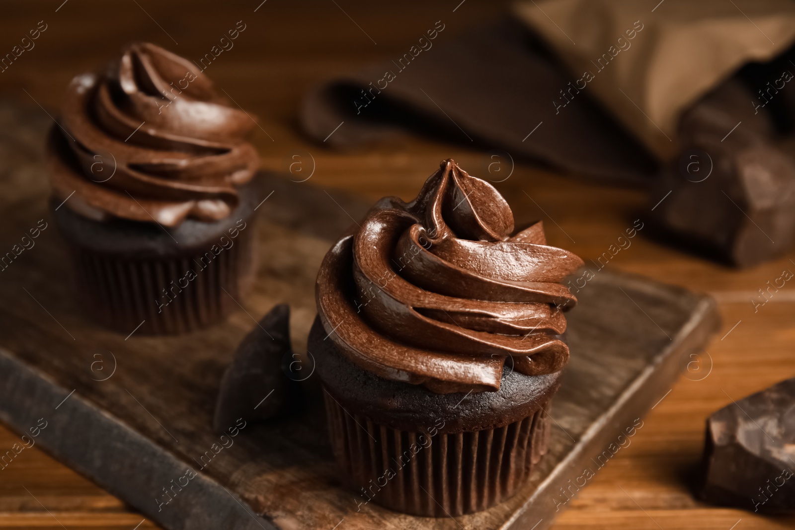 Photo of Delicious chocolate cupcakes with cream on wooden table