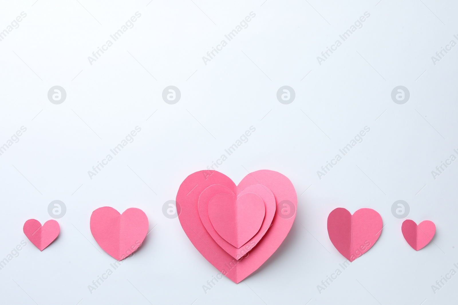 Photo of Pink paper hearts on white background, flat lay. Space for text