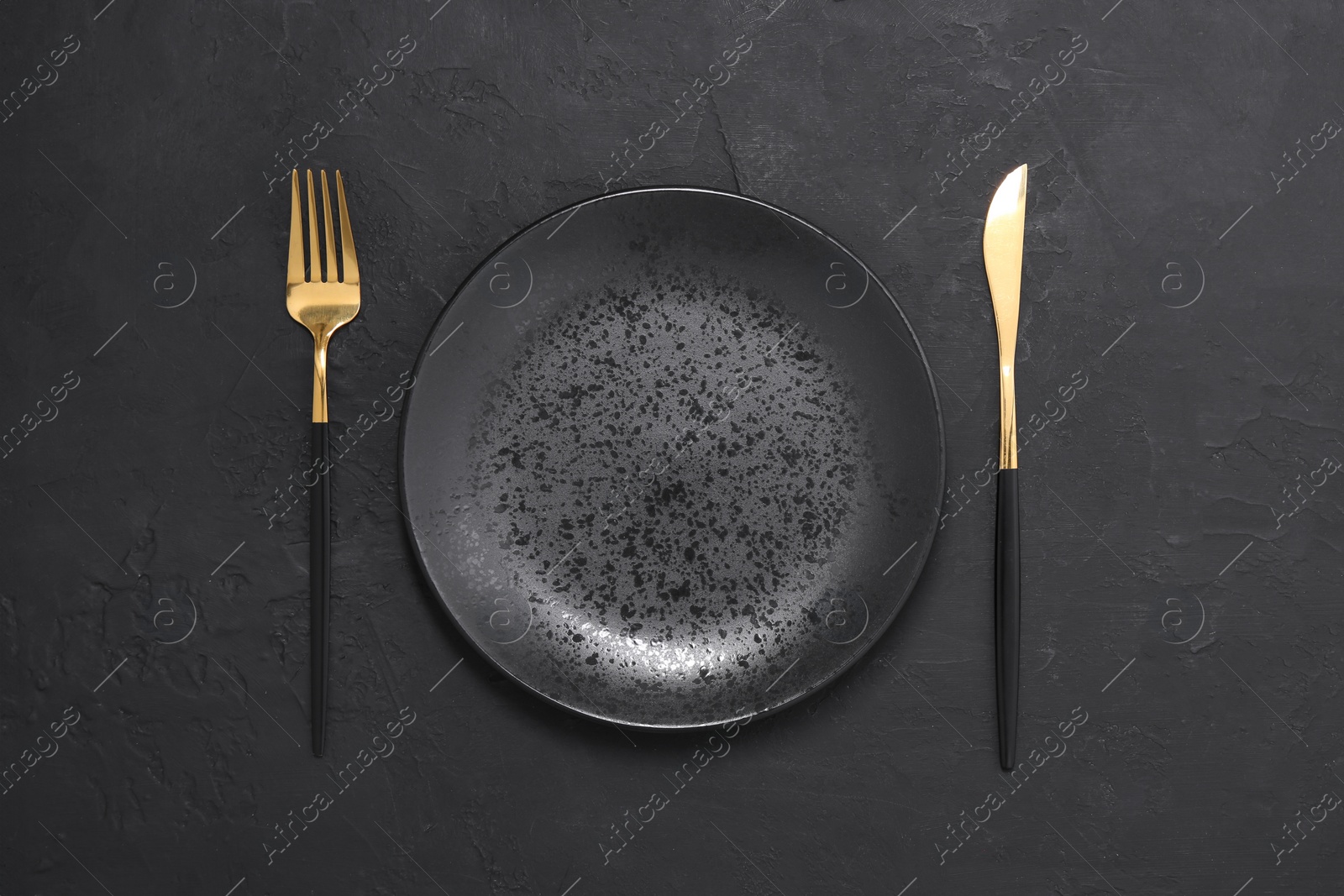 Photo of Elegant setting with shiny cutlery on black table, top view