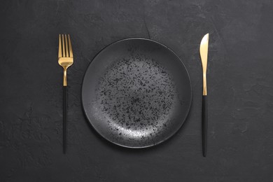 Photo of Elegant setting with shiny cutlery on black table, top view