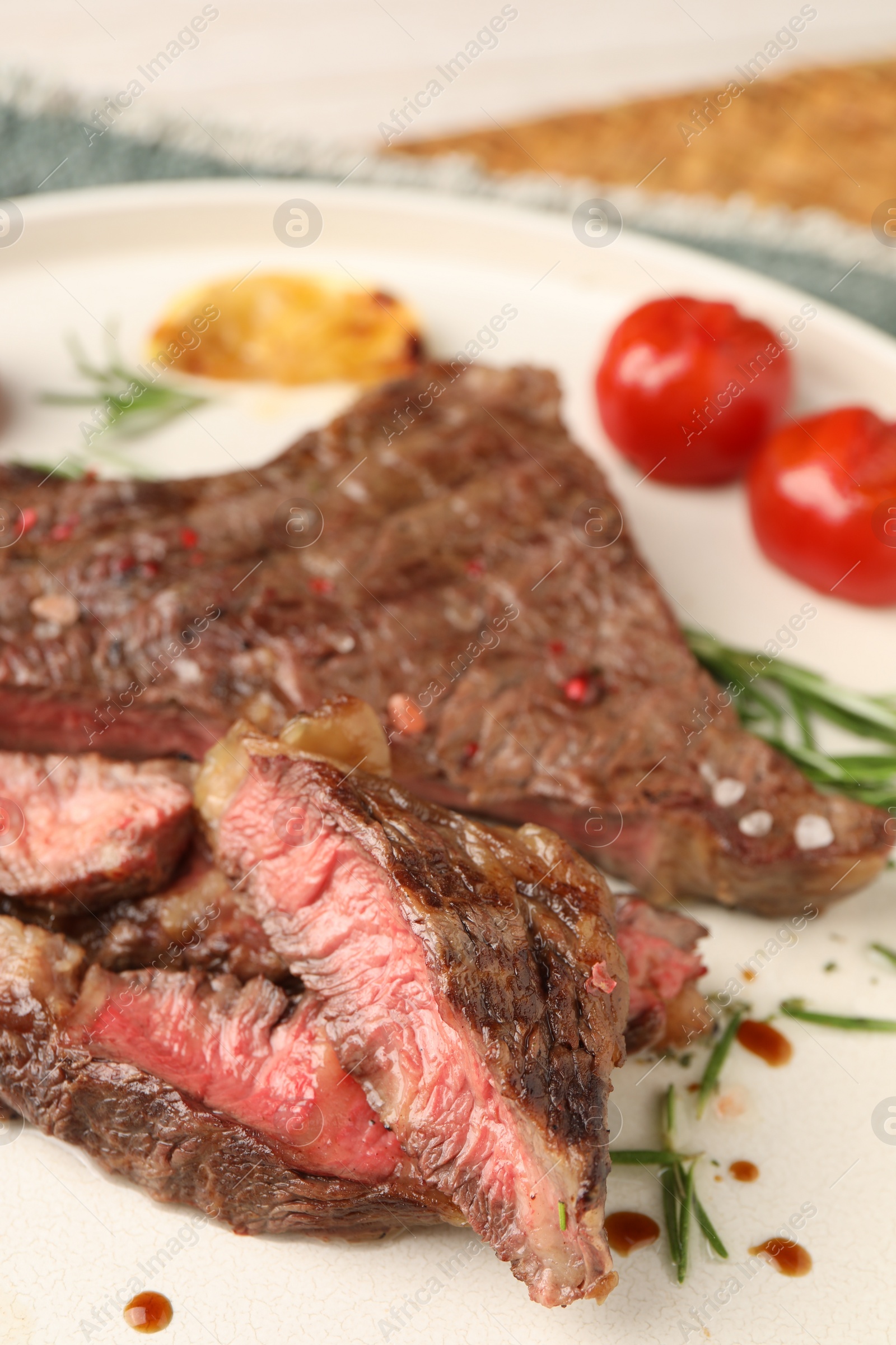 Photo of Delicious grilled beef steak, tomatoes and rosemary on plate, closeup