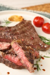 Photo of Delicious grilled beef steak, tomatoes and rosemary on plate, closeup