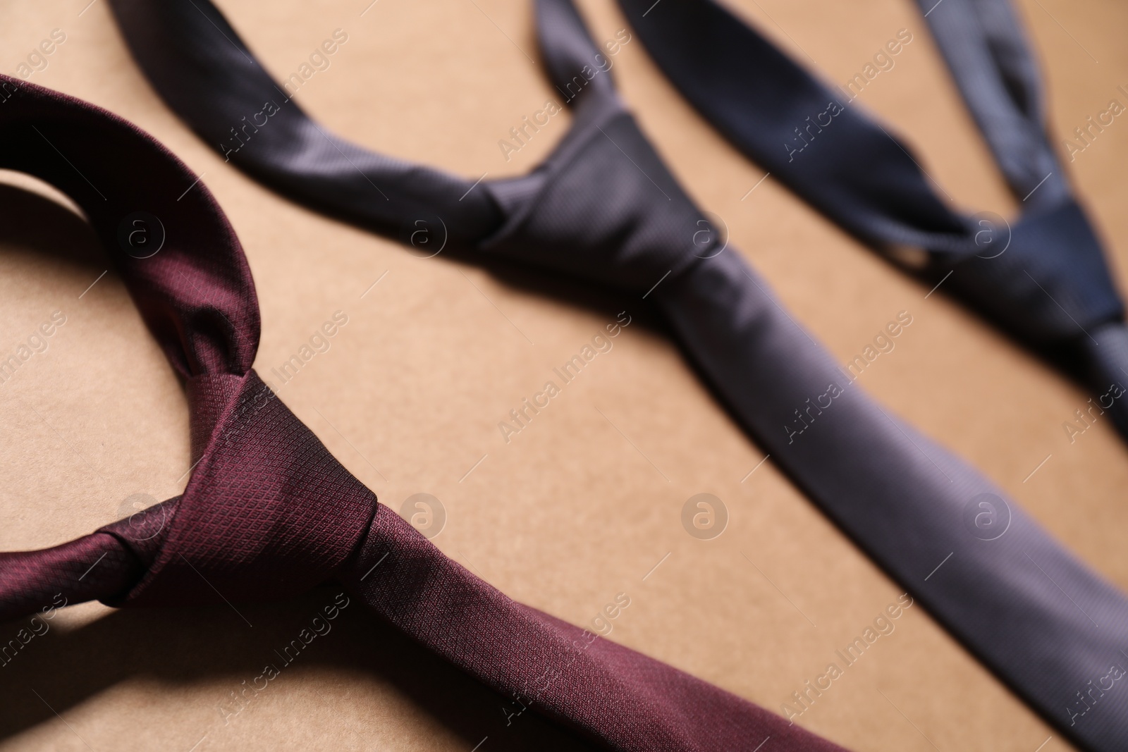 Photo of Different neckties on beige background, closeup view