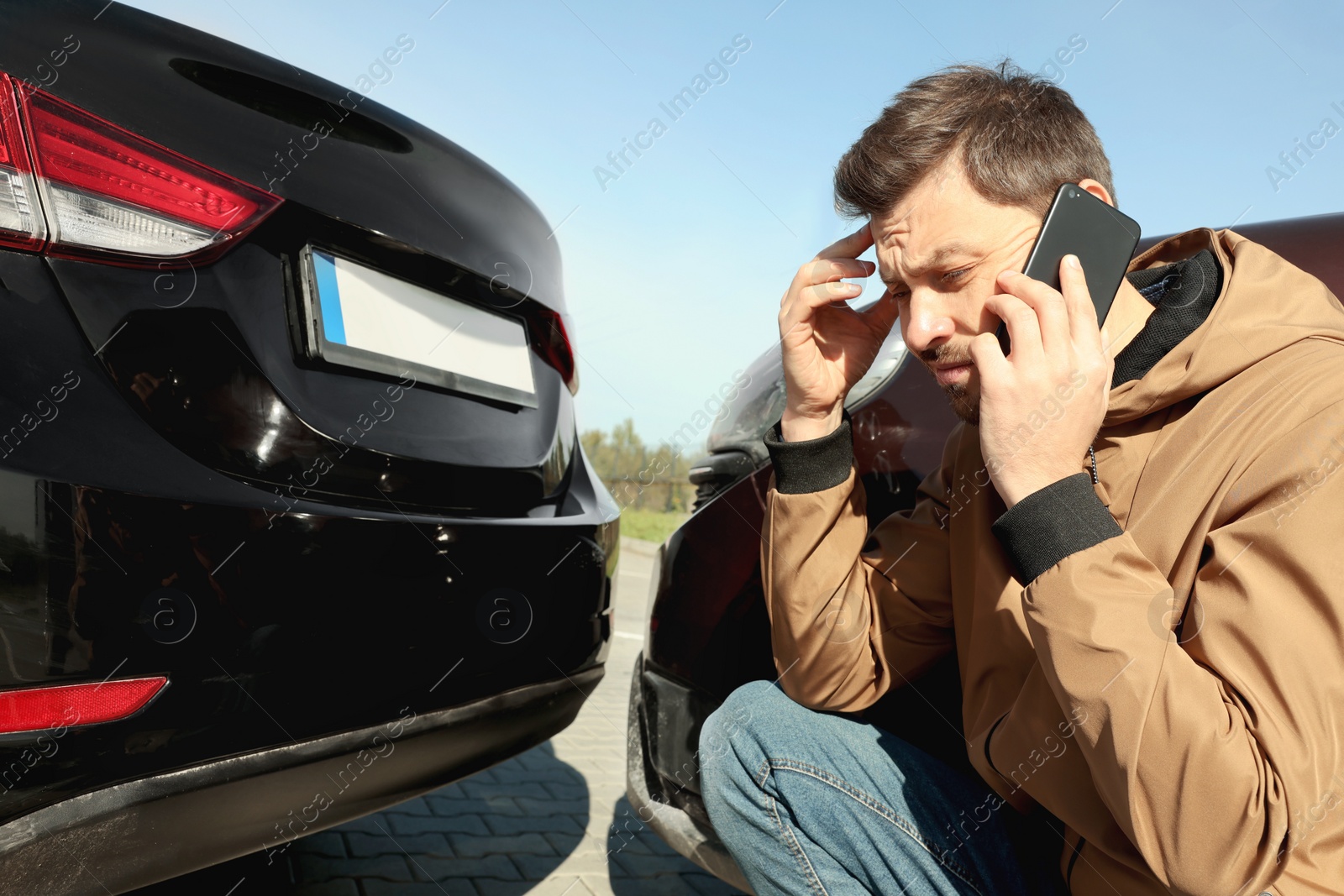 Photo of Man talking on phone near car with scratch outdoors Auto accident