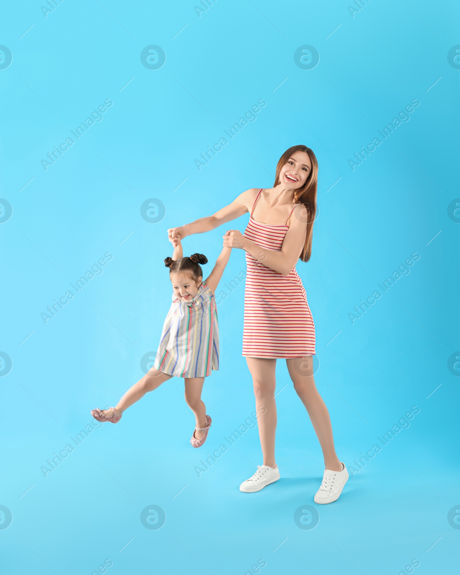 Photo of Young mother and little daughter having fun on light blue background