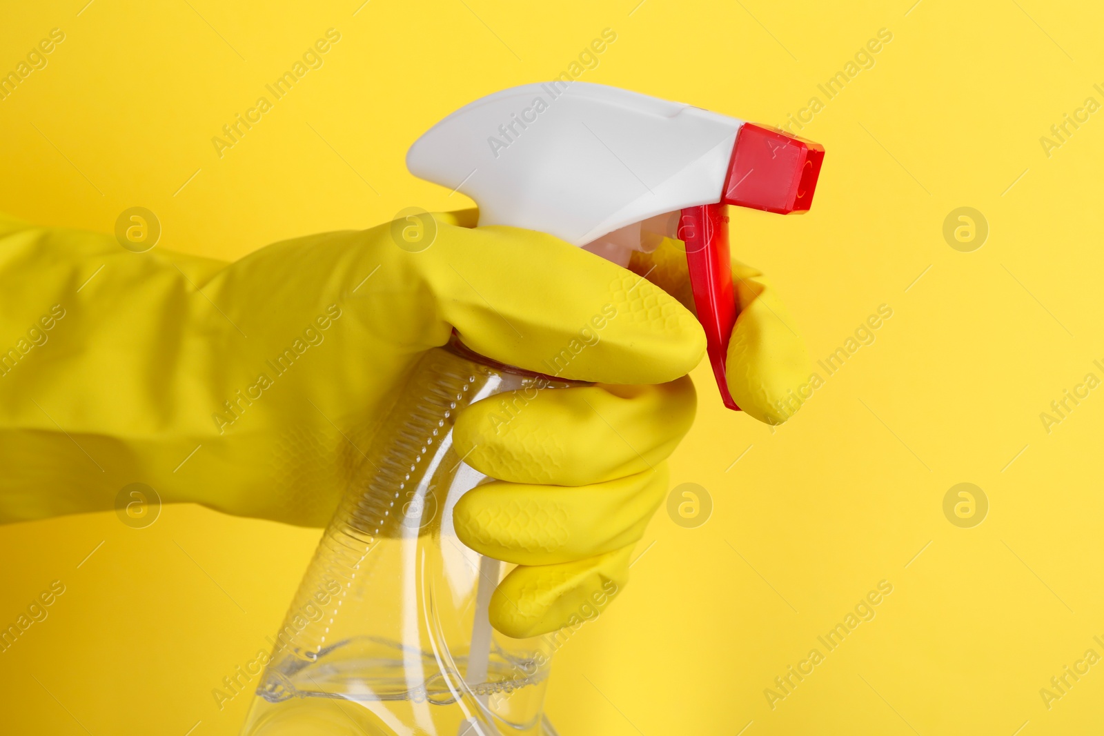 Photo of Woman holding plastic spray bottle on yellow background, closeup