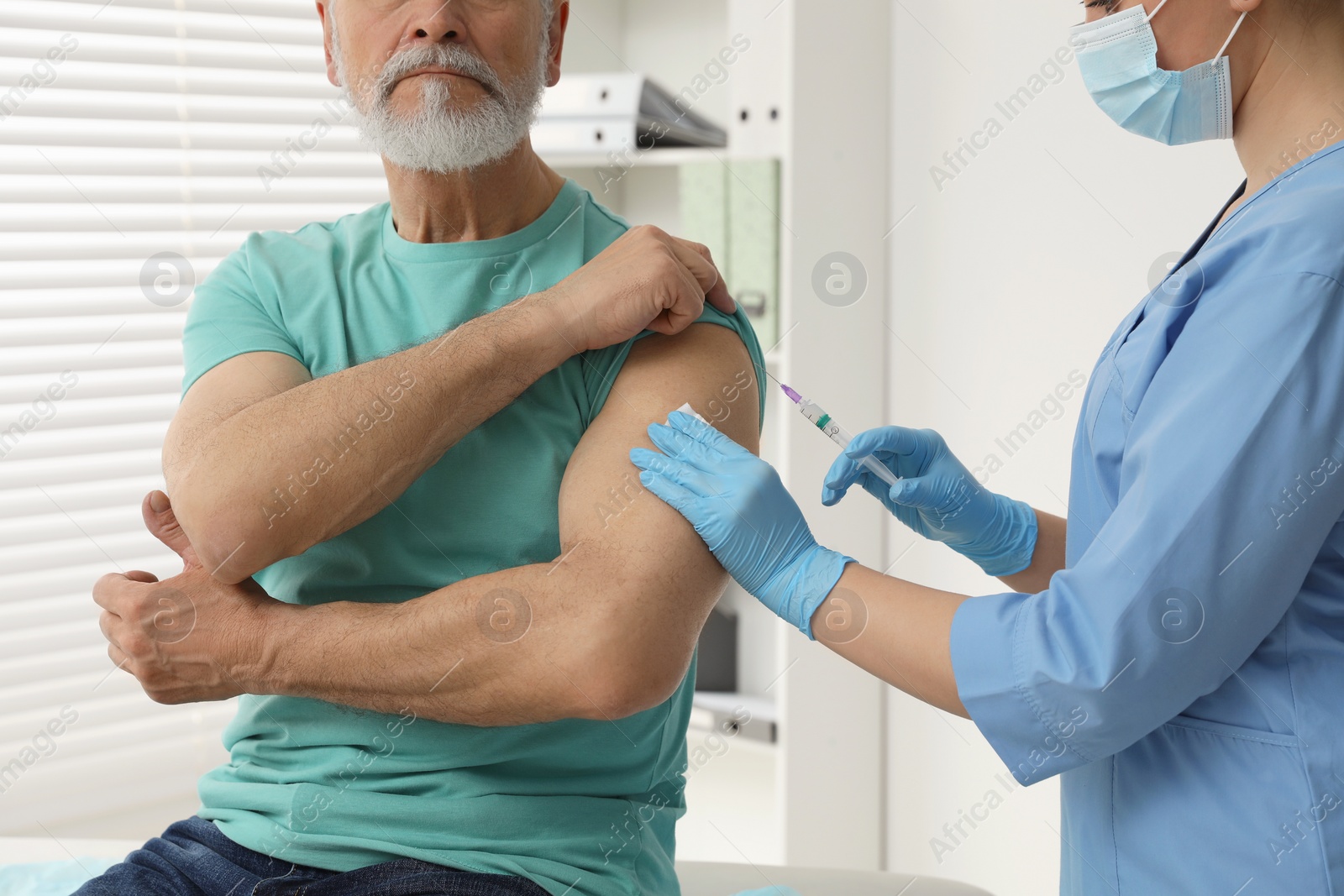 Photo of Doctor giving hepatitis vaccine to patient in clinic, closeup