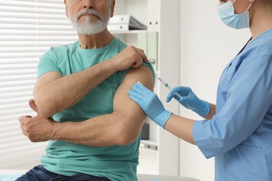 Doctor giving hepatitis vaccine to patient in clinic, closeup