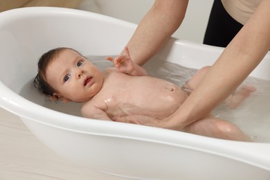 Mother bathing her little baby in bathtub, closeup