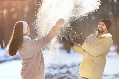Happy couple playing snowballs on winter day outdoors