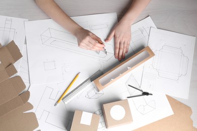 Photo of Woman creating packaging design at light wooden table, top view