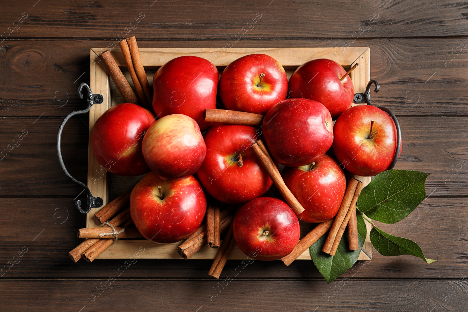 Photo of Fresh apples and cinnamon sticks on wooden table, top view