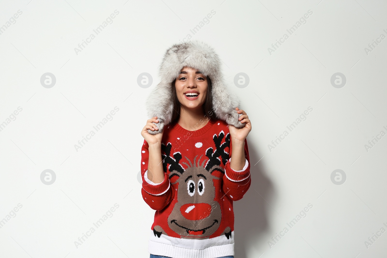 Photo of Young woman in Christmas sweater and hat on white background