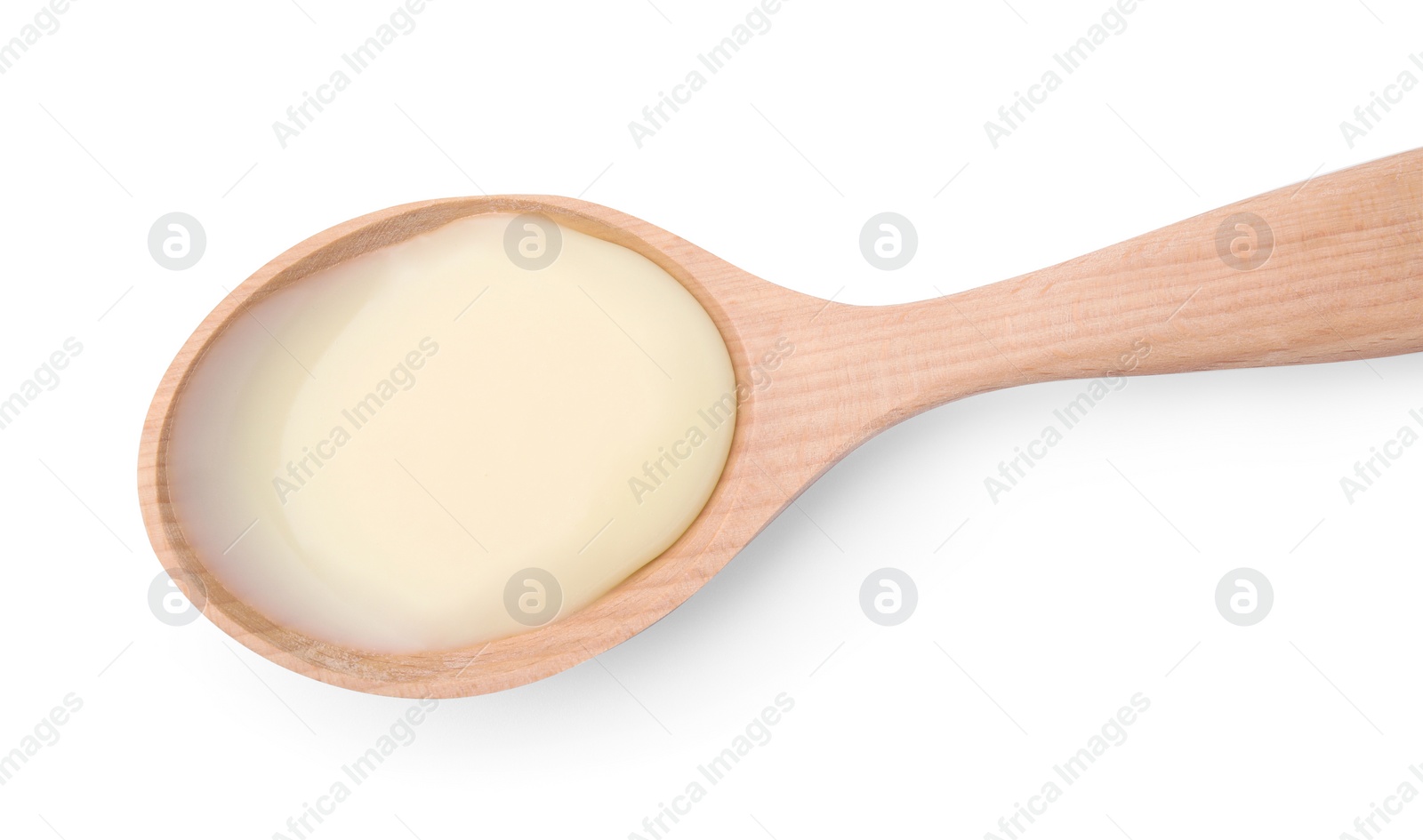 Photo of Wooden spoon with condensed milk isolated on white, top view