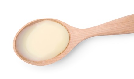 Photo of Wooden spoon with condensed milk isolated on white, top view