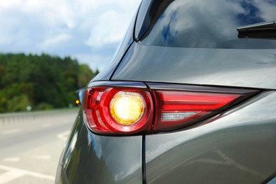 New black modern car on asphalt road, closeup of taillight