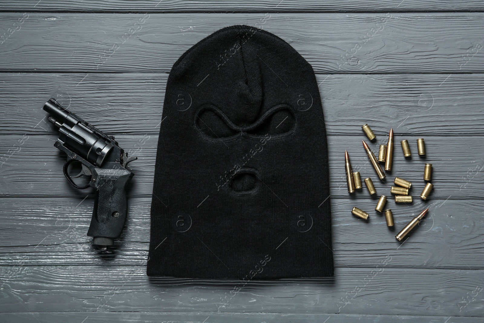 Photo of Balaclava, pistol and bullets on grey wooden table, flat lay