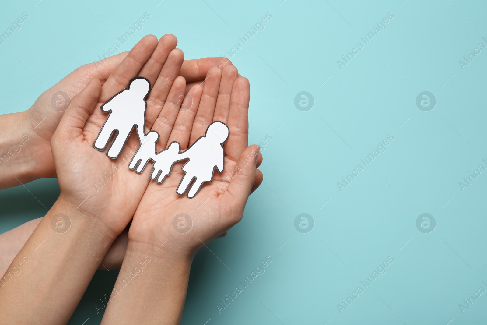 Photo of Couple holding paper family cutout on turquoise background, top view. Space for text
