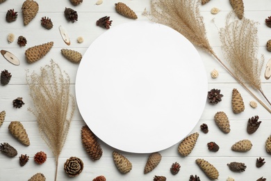Photo of Flat lay composition with pinecones and blank card on white wooden background, space for text