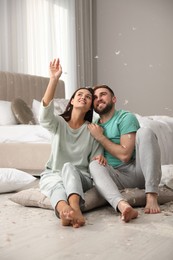 Happy young couple resting after fun pillow fight in bedroom