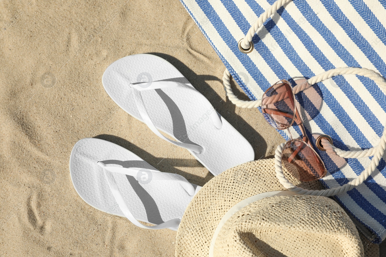 Photo of Flat lay composition with stylish beach accessories on sand