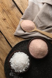 Photo of Different natural salt on wooden table, flat lay