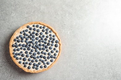 Photo of Tasty blueberry cake on gray background, top view with space for text