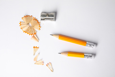 Short graphite pencils, shavings and sharpener on white background, top view