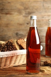 Photo of Bottle of delicious fresh kvass, spikelets and bread on wooden table