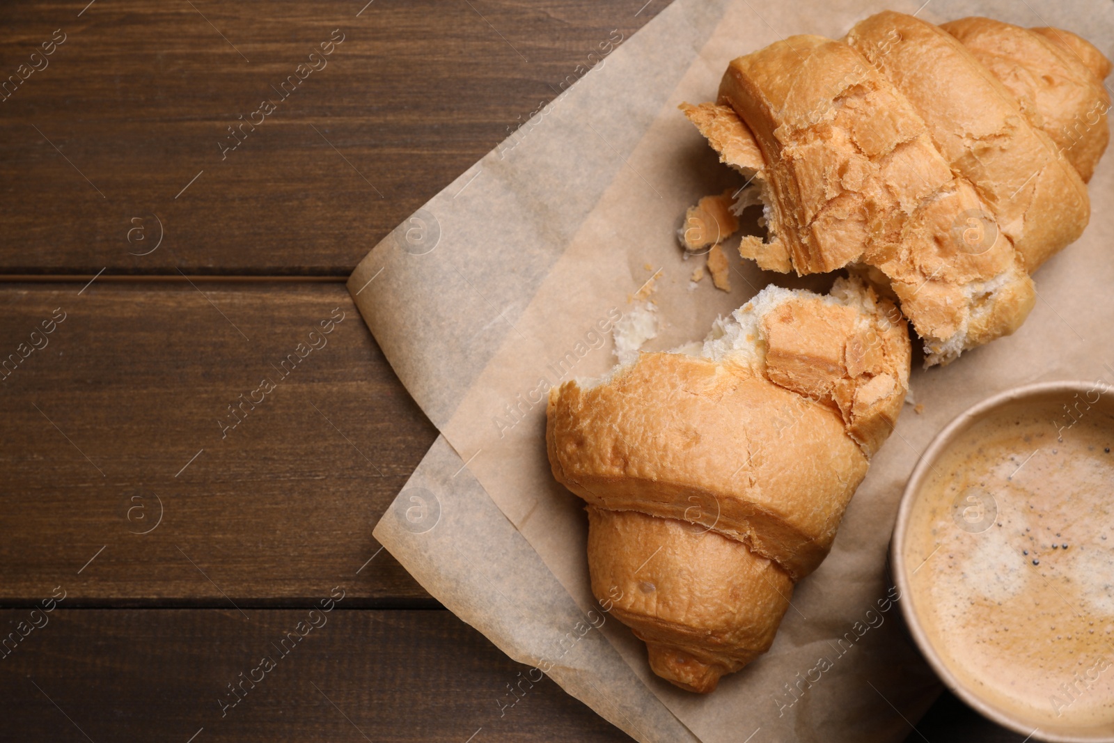 Photo of Fresh croissant and aromatic coffee on wooden table, flat lay. Space for text